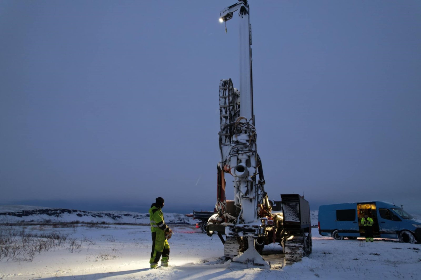 Drilling rig lit against the dusk sky during water drilling on site at Klaustur Charr in winter