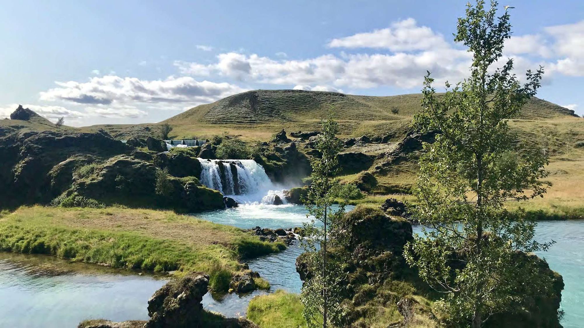 Turquoise spring water and waterfall in south Iceland